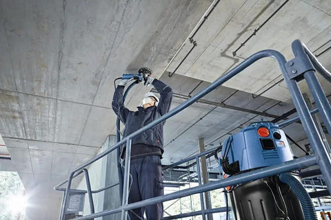 Worker using 5 Inch Diamond Cup Grinding Wheel For Concrete With Double Row Segments on ceiling, dust reducing design in action.