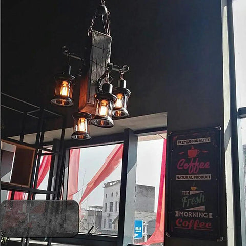 Industrial Vintage Wooden Hanging Pendant Light With Four Lantern Bulbs over a coffee shop window with coffee signs
