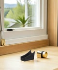 Black and gold U Shaped Chair Leg Protectors on hardwood floor for stability and wobble reduction; shown near window.