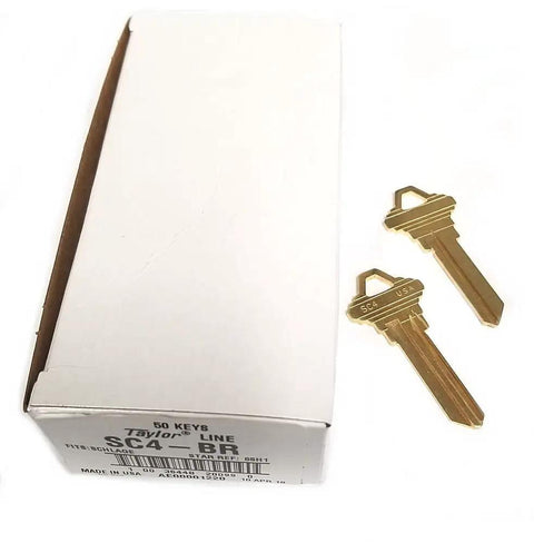 Box of SC4 BR Brass Key Blank For SCH C 6 Pin Keyway, 50 pack, with two brass key blanks lying beside it.