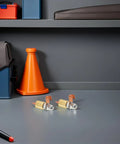 Welding Ground Clamp Assist Holder Two Pack with copper alloy base on gray surface, orange cone and toolboxes in background