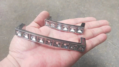 Close-up of two Six Pack U Shape Crystal Glass Drawer Pull Knobs For Cabinets And Dressers with Zinc Alloy Base in a hand.