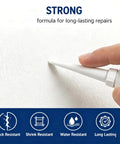 Hand applying Effortless Drywall Repair Kit With Paste Quick-Dry Patch For Holes And Cracks Scraper And Sandpaper to a white wall.
