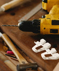 Heavy Duty Steel Belt Clip Hooks For Drill Drivers With Screws Rugged Tool Belt Clips For Secure On Site Tool Carry Rust Resistant Durable Replacement Clips That Stand Up To Tough Worksites., white steel replacement belt clips beside a drill driver on a workbench