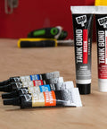 Tubes of Tank Bond Resin and Accelerator on a workbench, with two small black-and-blue labeled tubes in the foreground.