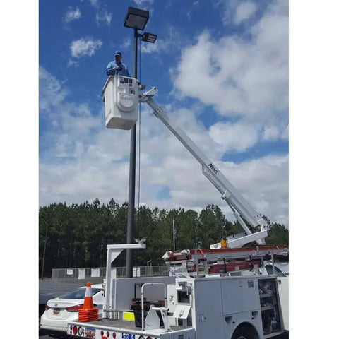 Technician installing Hella Bright 150W LED Shoebox Light With 18000 Lumens on pole in parking lot during daytime