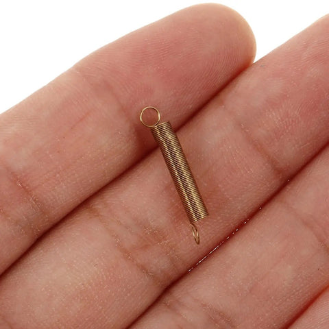 Clock Tension Springs Replacement Kit for Wall Clocks and Alarm Clocks, showing alloy extension spring on a hand