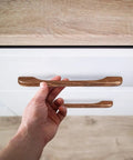 Hand installing Six Piece Walnut Wood Drawer Pulls Ergonomic Cupboard Handles For Kitchen Cabinets And Dressers Minimalist Solid Wood Hardware Easy DIY Replacement For Wardrobes on white drawer