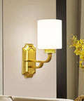Solid Brass Wall Sconce With Smooth White Glass Shade Modern E27 Light Fixture mounted on wall beside decorative flowers.