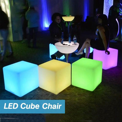 16-Inch Cordless LED Cube Light With Removable Panels glowing in blue, yellow, and green hues at a party setting.