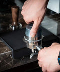 Barista tamping espresso using portafilter on Espresso Tamping Mat For Baristas Grippy Black Food Grade Silicone Pad 8 Inch By 6 Inch Waterproof