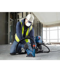 Worker using a power tool on concrete floor inside building