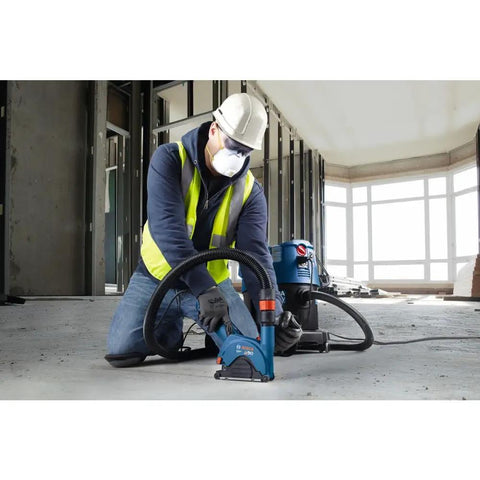 Worker using a power tool on concrete floor inside building