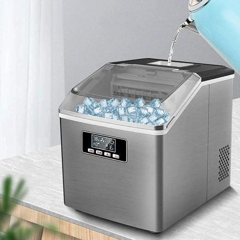 Smooth Operator Home Bar Ice Cube Maker With A Transparent Cover And Brushed Metal Frame on countertop filled with ice cubes.