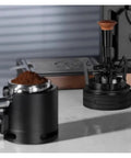 Smooth Operator Espresso Rotary WDT Tool And Coffee Stirrer With Built In Dosing Funnel Stand For Even Powder Distribution and Knockout Barista Shots At 54mm on a countertop with ground coffee.