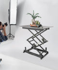 Built Like A Tank Electric Scissor Lift Table With Smooth Hydraulic Action And Wireless Remote For Easy Warehouse Material Handling Holds 180 Pounds Securely And Folds Flat For Storage, shown in studio with decorative items.