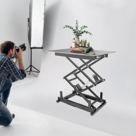 Built Like A Tank Electric Scissor Lift Table With Smooth Hydraulic Action And Wireless Remote For Easy Warehouse Material Handling Holds 180 Pounds Securely And Folds Flat For Storage, shown in studio with decorative items.