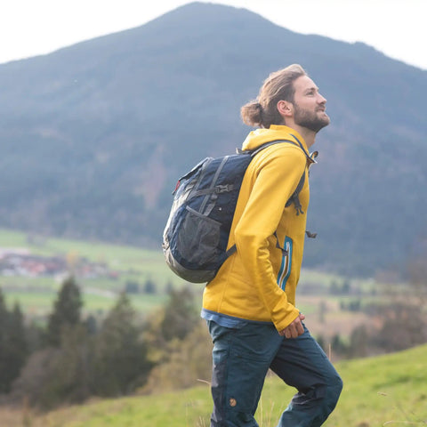 Person hiking with Ultralight 30L Packable Hiking Backpack For Women And Men Foldable Travel Daypack, mountain backdrop.