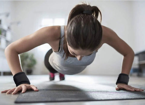 Woman doing push-ups wearing 2 Pack Wrist Wraps For Carpal Tunnel Relief And Pain Prevention, Flexible Adjustable Wrist Brace For Men And Women