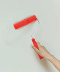 Red Grain Pattern Paint Roller For Wall Texturing With Ergonomic Plastic Handle in use against white wall.