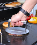 Stainless Steel Burger Press Round 6.2 Inch Smasher For Flat Top Griddles And Grills pressing a patty on the grill