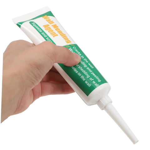 Hand squeezing tube of Drywall Repair Putty Paste For Quick Hole Patching And Wall Mending Cream Safe Ingredients Easy No Mess Smoothing Smear On Spackle