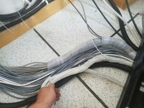 Person organizing cables with 11mm ID by 12mm OD Spiral Cable Wrap Tube 10 Meter Roll Clear White PE Wire Organizer in use