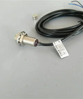 Front view of Amazon M12 magnetic switch sensor with threaded metal housing, mounting nut, and black cable