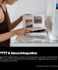Person using LoRa Based Smart Wireless Thermometer With No WiFi Needed And Long Range Temperature Monitoring For Freezers Fridges Greenhouses And Pet Cages App Alerts Via Email And Text Battery Lasts Up To Five Years Hub Required near a clock on a desk.