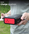 Person holding Massive 24000mAh Portable Power Bank With 110V 65W AC Outlet 88.8Wh Power Station while charging phone outdoors.