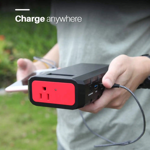 Person holding Massive 24000mAh Portable Power Bank With 110V 65W AC Outlet 88.8Wh Power Station while charging phone outdoors.