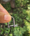 Close-up of Stainless Steel Mini D Shackle 4mm For Paracord Jewelry And Everyday Outdoor Gear held between fingers outdoors.