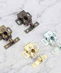 Four 20Pcs Double Roller Door Catch Latch For Cabinet Doors And Wardrobes in different finishes on a marble surface.