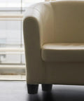 Beige armchair with black legs near a window.