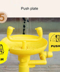 Close-up of yellow push plate on stainless steel 304 emergency eyewash station floor mounted with dual nozzles.