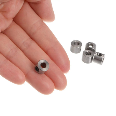 Hand holding Ten Pack 4mm Bore Shaft Collars With Set Screws Stainless 304 Steel 9mm OD 7mm Thick for positioning and spacing
