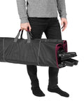 Person carrying the All In One Portable Folding Hammock With Metal Frame And Retractable Canopy Ideal For Camping Patio Or Backyard Chill Sessions Side Pockets Easy Zip Carry Sling Red in a black zippered sling bag.