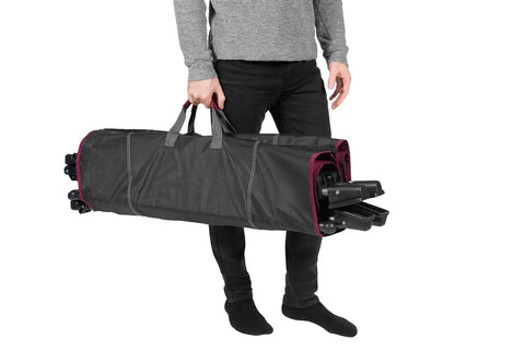 Person carrying the All In One Portable Folding Hammock With Metal Frame And Retractable Canopy Ideal For Camping Patio Or Backyard Chill Sessions Side Pockets Easy Zip Carry Sling Red in a black zippered sling bag.