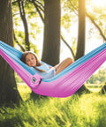 Girl relaxing in pink and blue Kids Camping Hammock For Outdoor Fun Ultralight Gear With Tree Straps And Carabiners