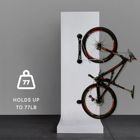 Heavy Duty Wall Mounted Bike Rack For Mountain Bikes No Lift Easy Rear Wheel Loading Space Saving Garage Storage Solution For Home Or Bike Park Sturdy Steel With UV Treated Plastic Holds Up To 77 Lbs displaying a bike vertically.