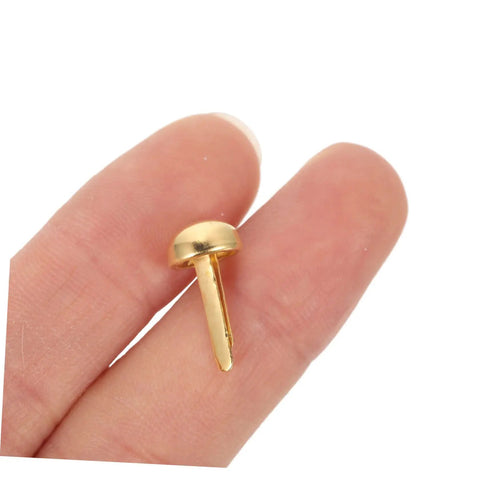 Hand holding a single gold fastener from 100 pcs decorative nails for DIY projects antique miniature fasteners for scrapbooking hinges and home decor wear