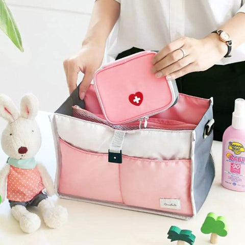 Person placing a mini pink first aid kit into a larger organizer. Pink Mini Outdoor First Aid Kit Bag For Travel And Everyday Use visible.