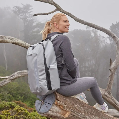 Woman with Fireproof Bug Out Backpack For Docs And Tech, 20L Water-Resistant Go Bag That Withstands 1832 Fahrenheit, in a foggy forest.