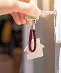Hand holding a key with a Premium Braided Pu Leather Key Fob with Solid Metal Hardware, featuring a burgundy woven strap.