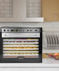 No Sweat Electric Food Dehydrator With Digital Temperature Control And Smart Timer, displaying snacks and herbs in BPA-free trays.