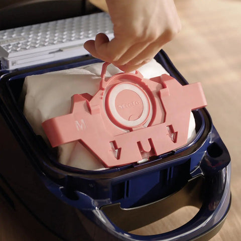 Hand inserting HyClean Air FJM Vacuum Bags for Compact C1 and C2 Canisters, showing easy bag change mechanism.