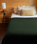 Olive bed with Beefy Warmth And Rugged Durability Military Wool Blanket for outdoors camping picnics travel stadium events and survival kits.
