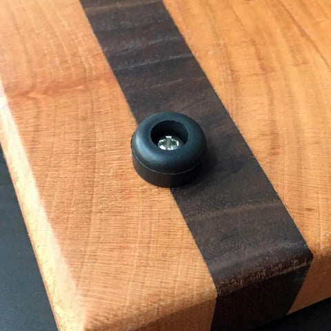 Close-up of a cutting board with 25 Soft Rubber Feet With Stainless Screws For Cutting Boards And Electronics attached.