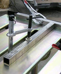Close-up of Worksite Ready Welding Table Pro Grade With 1.1 Inch Slot Top Adjustable Height And Tilt Casters For Easy Mobility Retractable Guide Rails Eccentric Leveling Feet Three Position Angled Tabletop For Horizontal 30 Degree Or Folded Storage Use showing clamped setup.