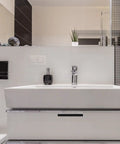 Modern bathroom interior with white sink, chrome fixtures, tile backsplash, and decorative accents